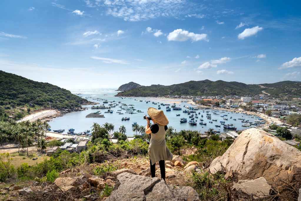 woman photographing vinh hy bay in vietnam from a hill