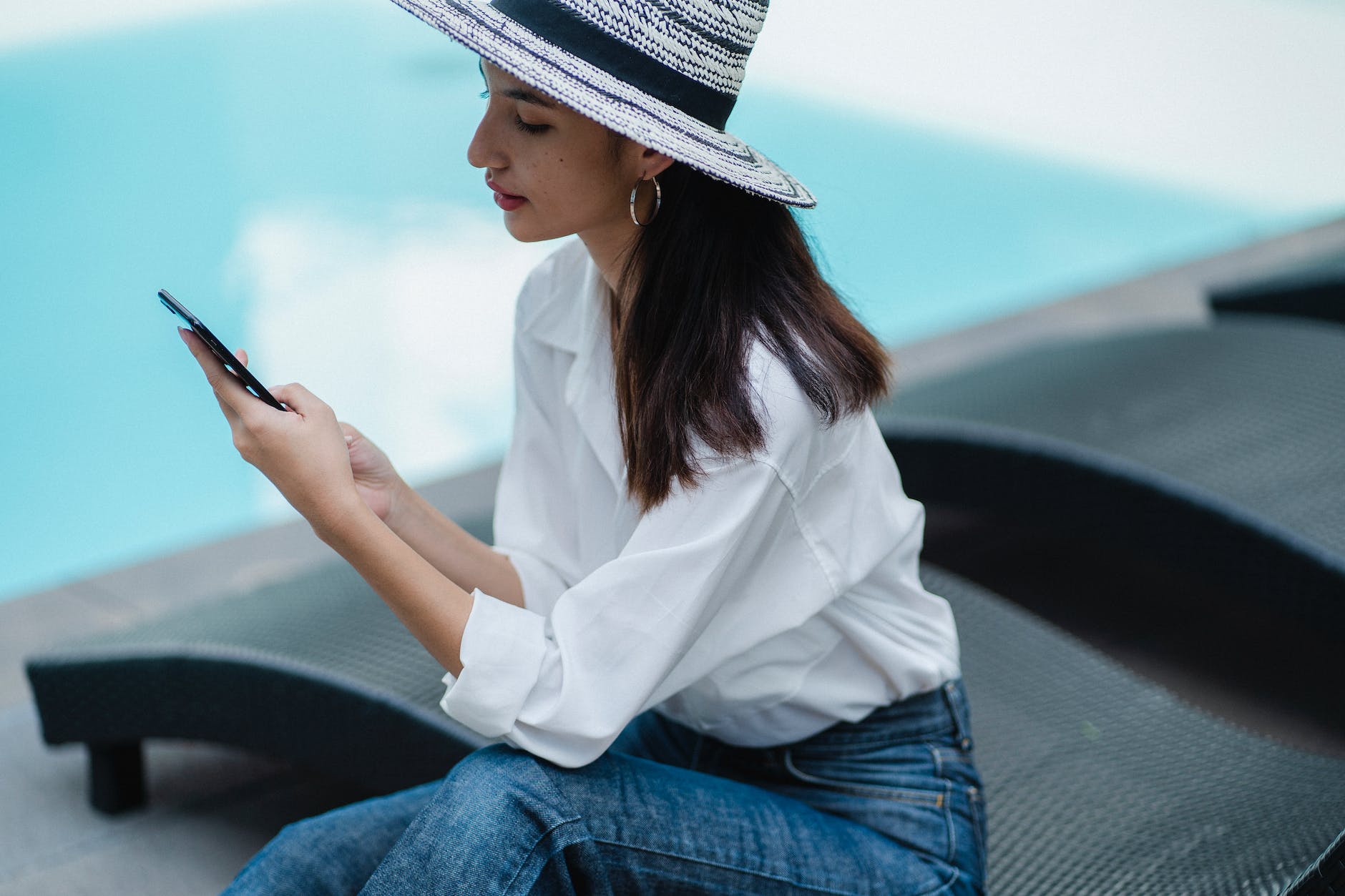 gorgeous young ethnic lady using smartphone at poolside